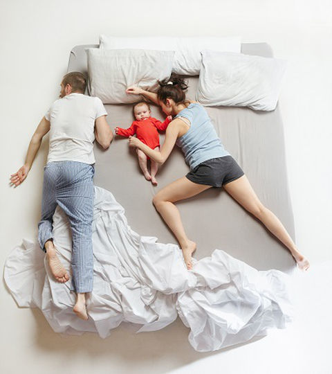 parents with a newborn child sleeping on a mattress